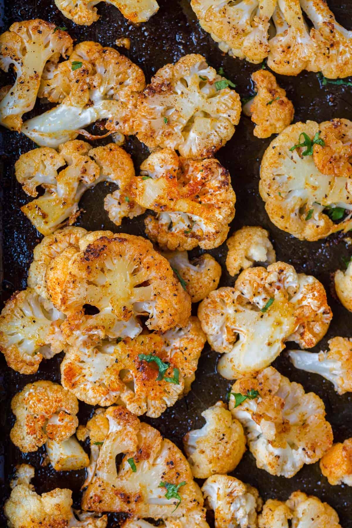 Roasted cauliflower florets seasoned with herbs and spices on a baking sheet