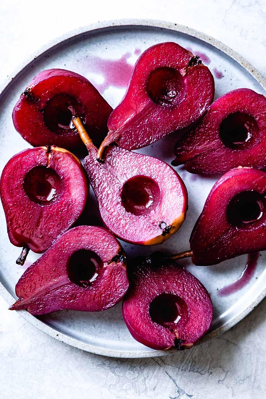 Pears halved and poached, arranged on a plate, with a glossy appearance