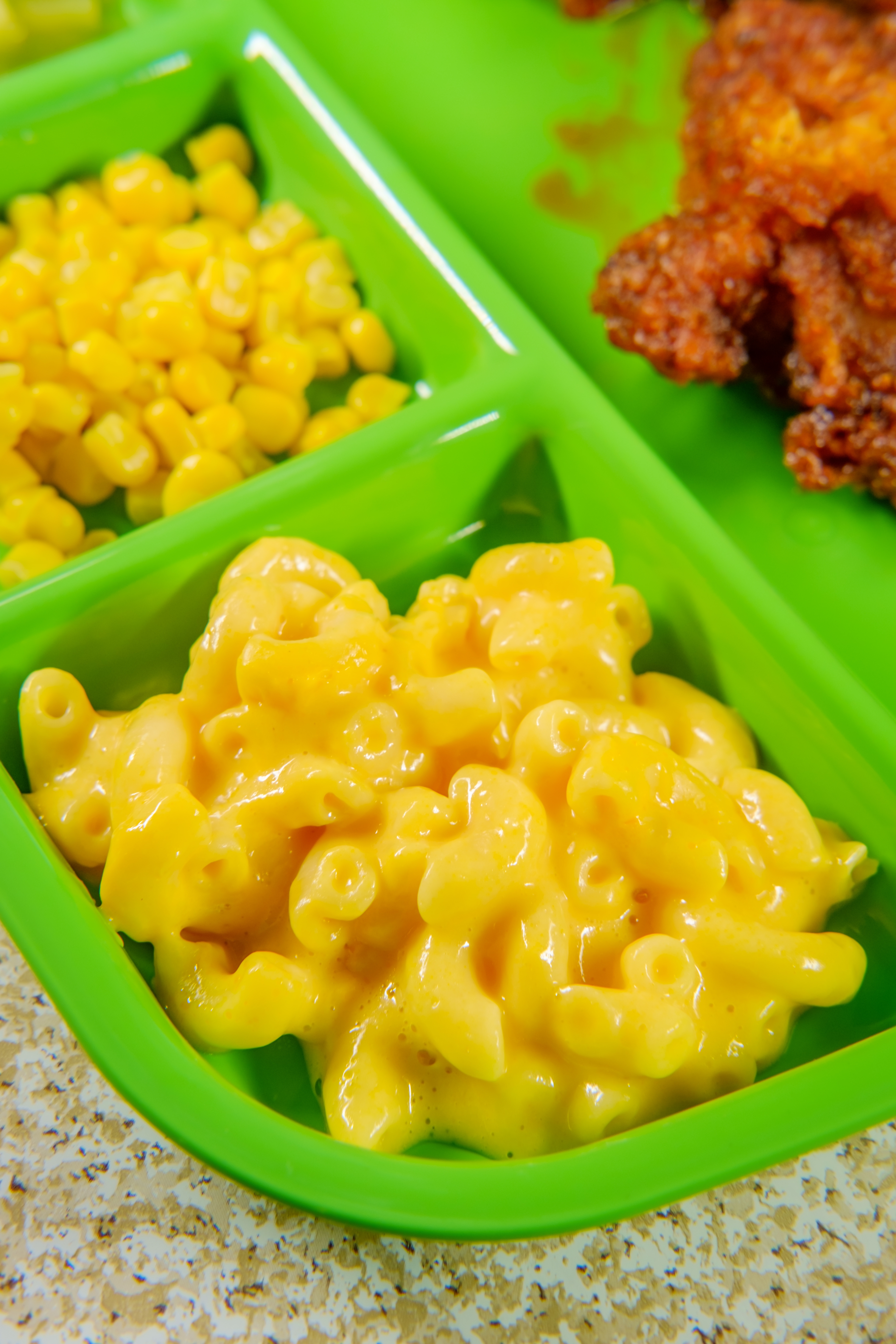 Macaroni and cheese with corn and fried chicken served on a green tray