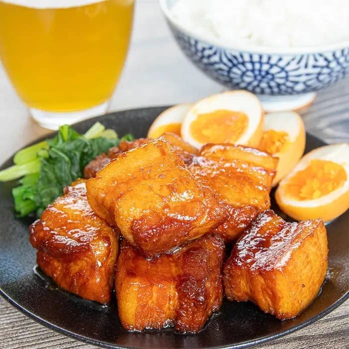 角煮、半熟卵、ほうれん草、ご飯、飲み物が皿に盛られている食事シーン。