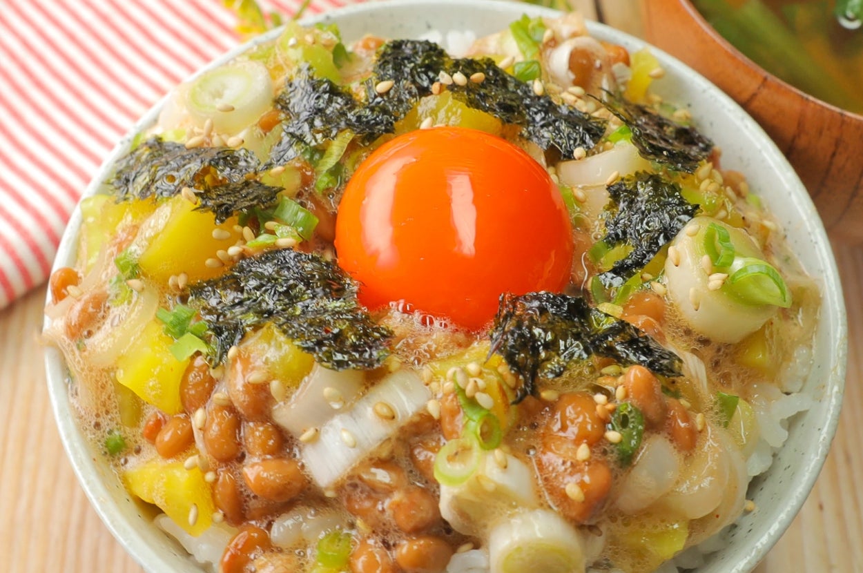 納豆、海苔、ネギ、卵黄がのったご飯の丼。そばに味噌汁。