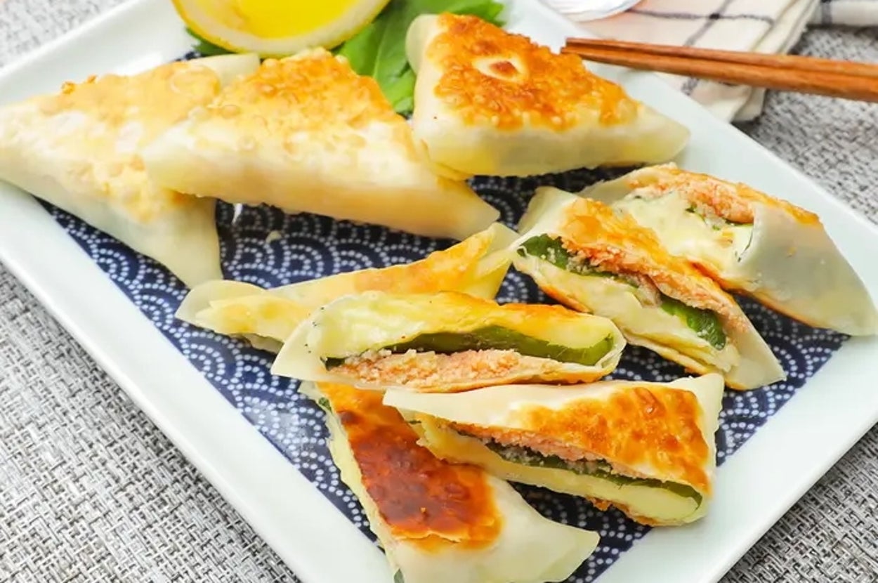 お皿に盛り付けられた揚げ餃子と柑橘のくし切りの様子。飲み物と箸が添えられている。