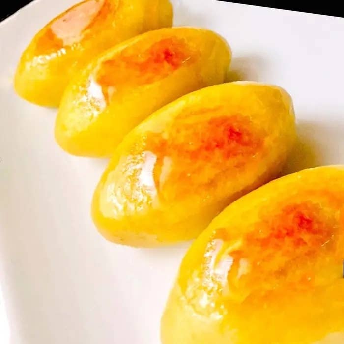 4つの艶やかなスイートポテトが白い皿に並べられています。