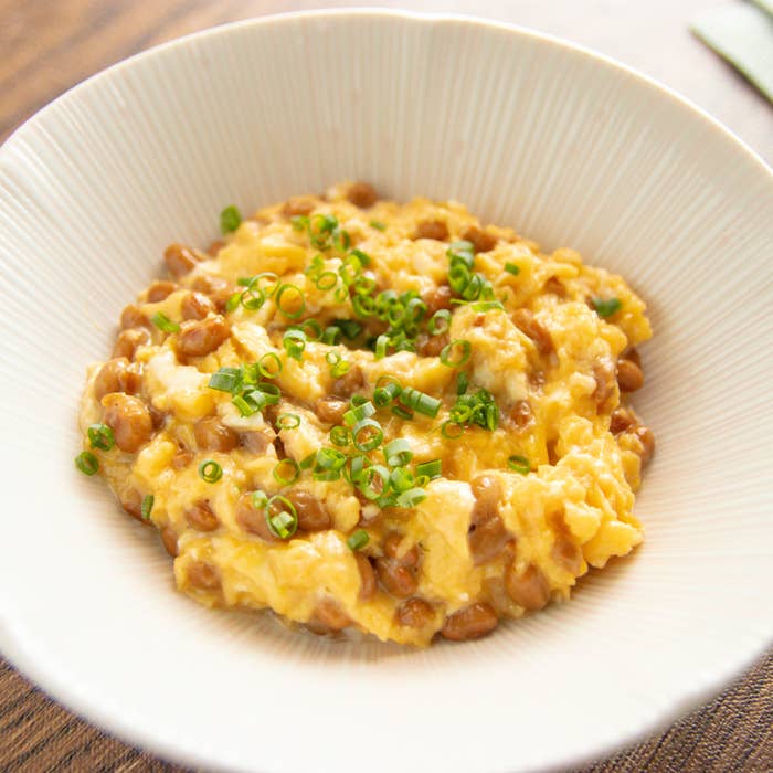 納豆と卵のふわふわ炒め。白いボウルに納豆とスクランブルエッグが盛られ、ネギがトッピングされています。