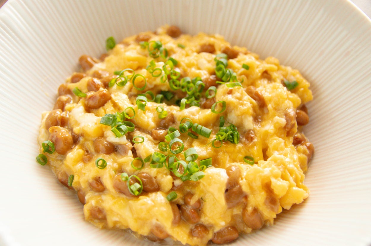 お皿に盛り付けられた納豆と卵の料理。刻んだネギがトッピングされている。