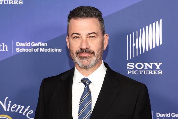 Jimmy Kimmel in a suit and striped tie at an event with backdrop logos including Sony Pictures and David Geffen School of Medicine