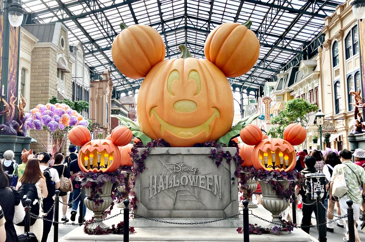 ディズニーのハロウィーンイベントでの巨大なミッキーマウスのカボチャディスプレイ。多くの来場者が周囲に集まる。