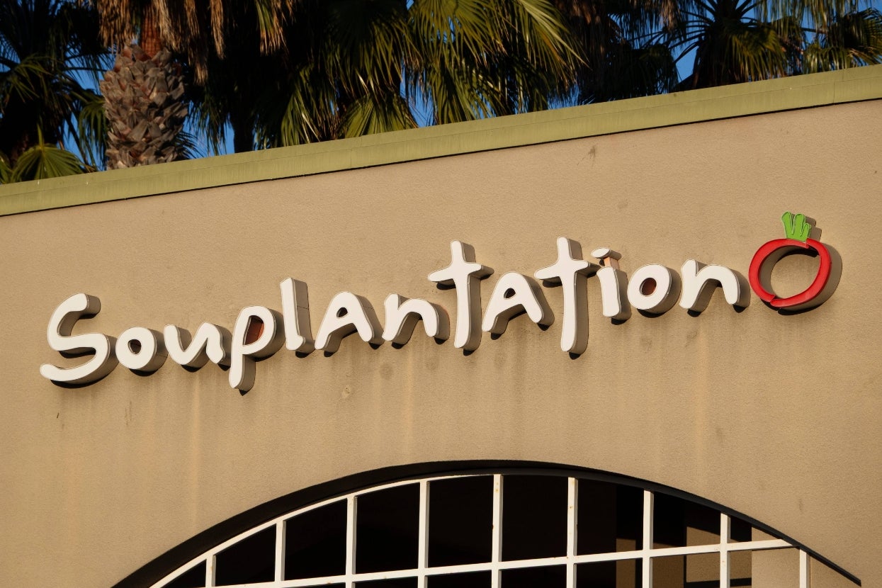 Souplantation restaurant sign on building exterior with tropical palm trees in the background