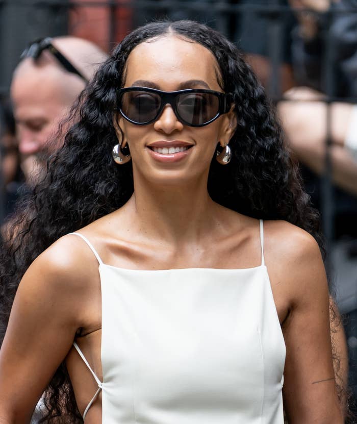 19 Celebs Who Welcomed Babies Super Young 3 Solange Knowles wearing sunglasses and a white outfit smiling while out in public