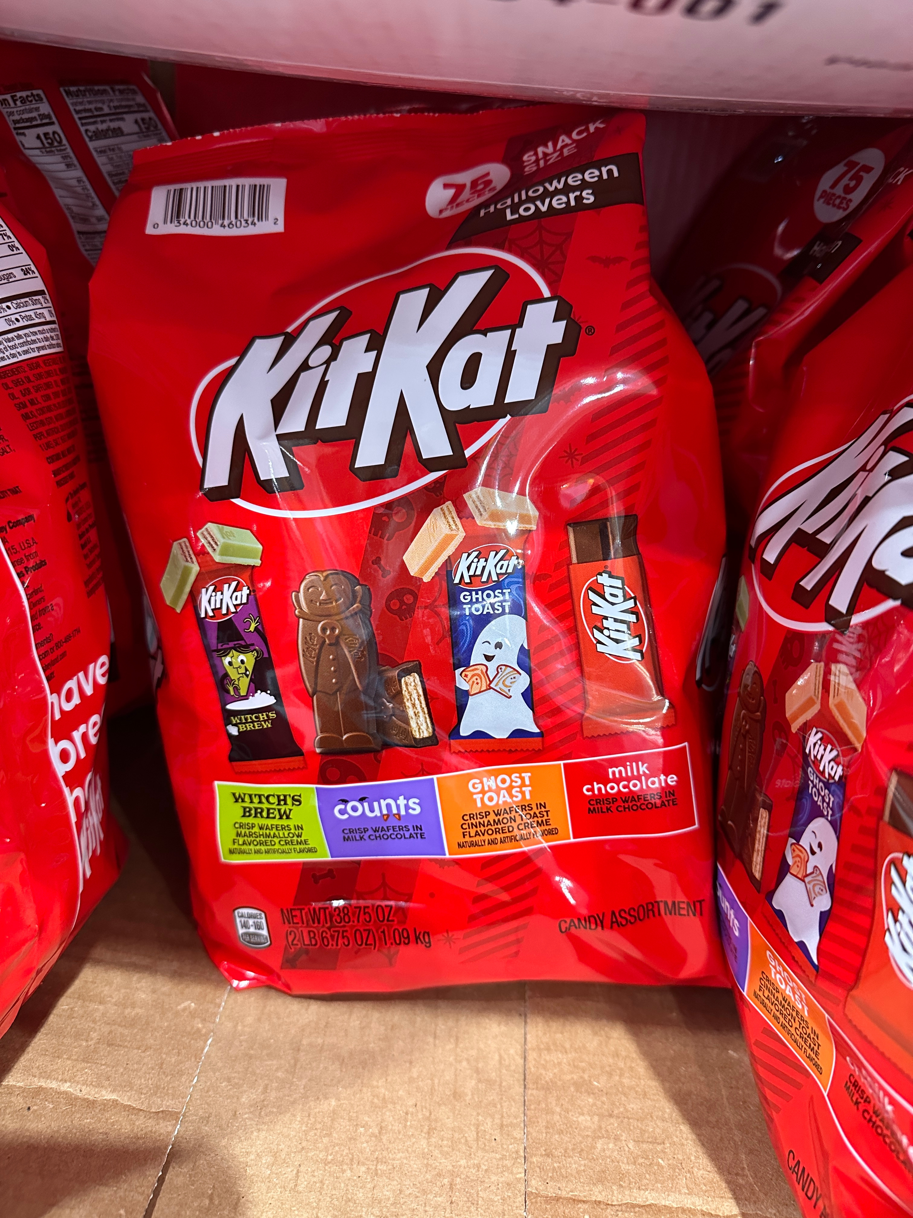 Bag of KitKat candy with various themed wrappers, including witch's brew and ghost popcorn flavors, displayed on a shelf