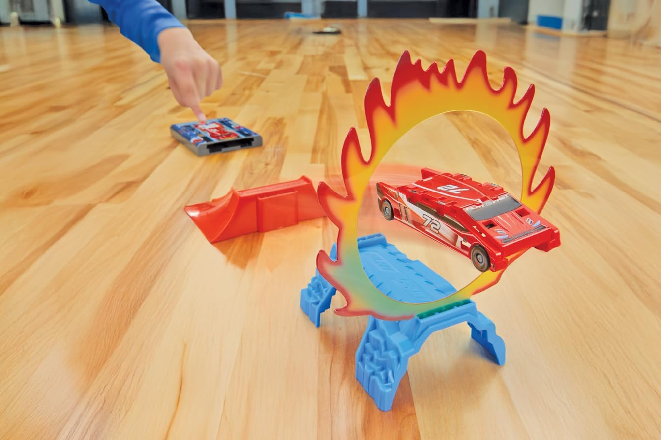 Toy cars race through a plastic flame hoop on a wooden floor, showcasing a playset for children