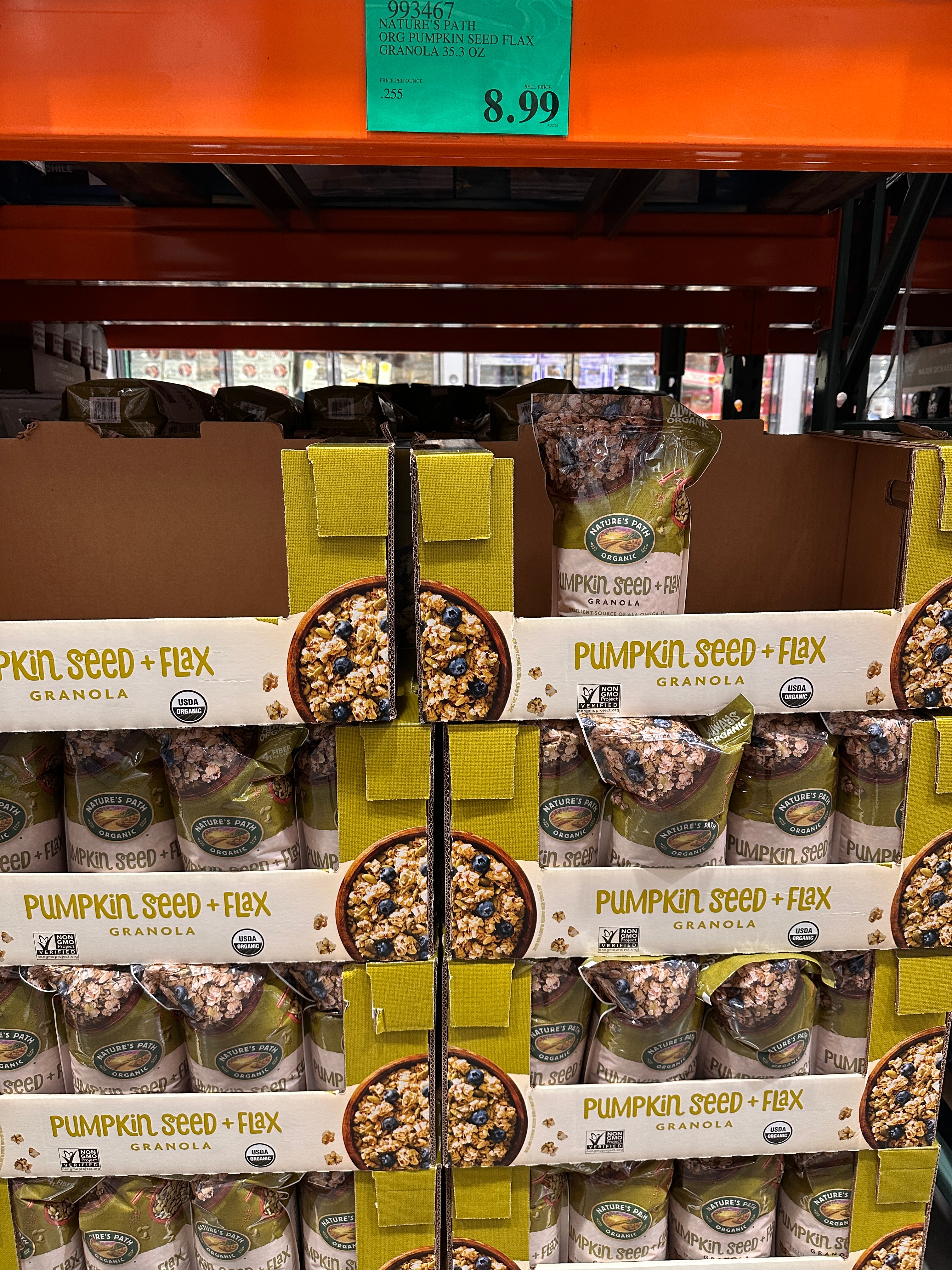 Packages of Pumpkin Seed + Flax Granola are stacked on a warehouse shelf, priced at $8.99