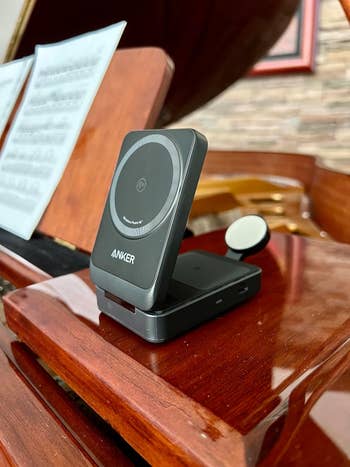 Anker wireless telephone charger connected a woody piano, with euphony sheets successful the background