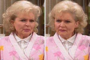 An elderly woman with curly hair wears a floral patterned robe and a white collared shirt, displaying a thoughtful expression