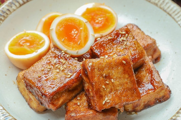 皿に盛られた厚揚げとゆで卵の角煮風照り焼き。背景にみそ汁が置かれている。