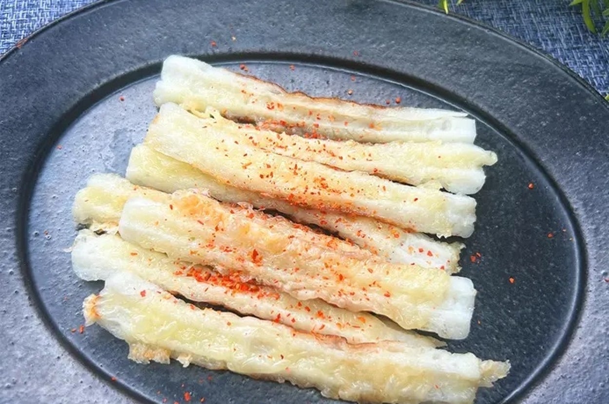 お皿に盛られた焼きちくわ、上にスパイスがかけられている。背景には緑の植物が見える。