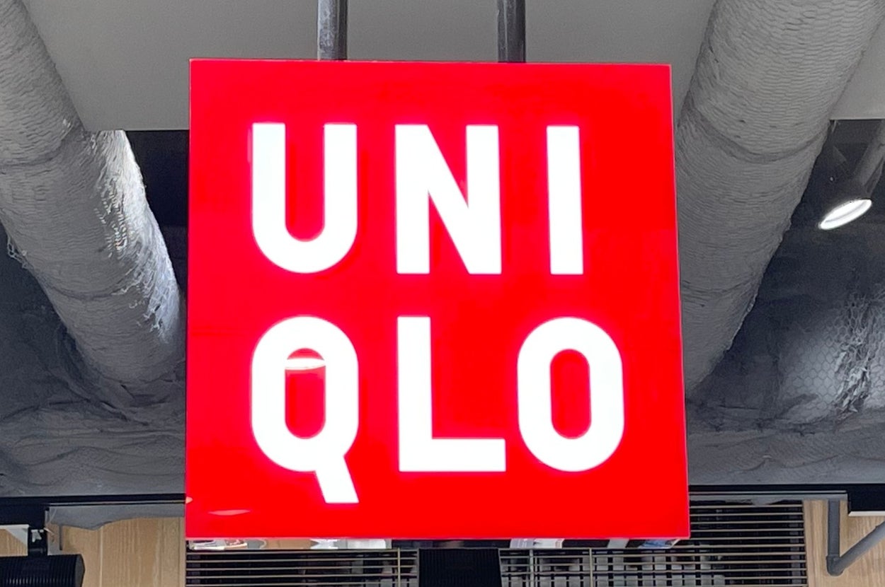 Uniqlo store interior with a prominent red and white logo sign hanging from the ceiling