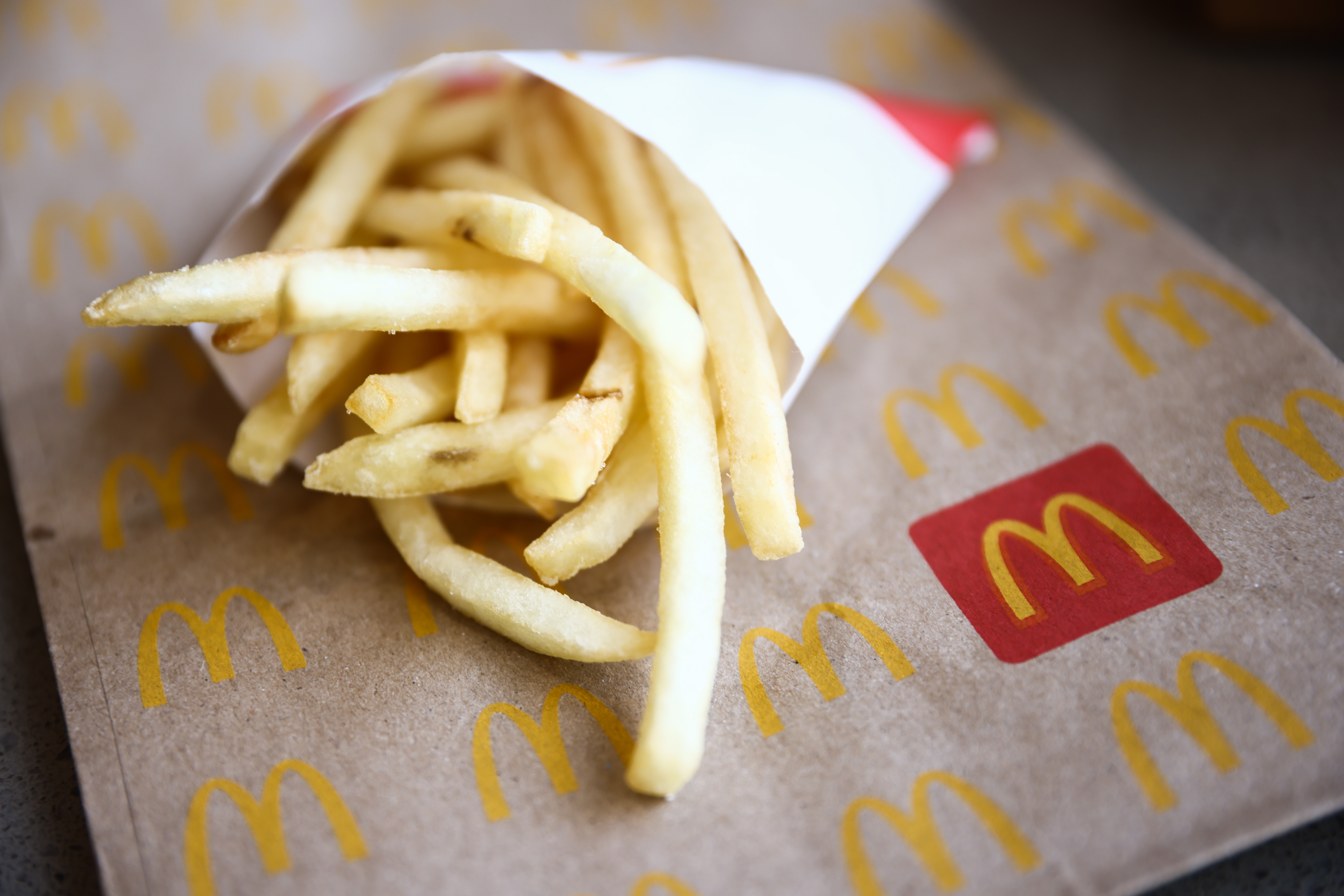 Fries spilling from a paper sleeve onto a McDonald's bag, showcasing a classic fast-food snack