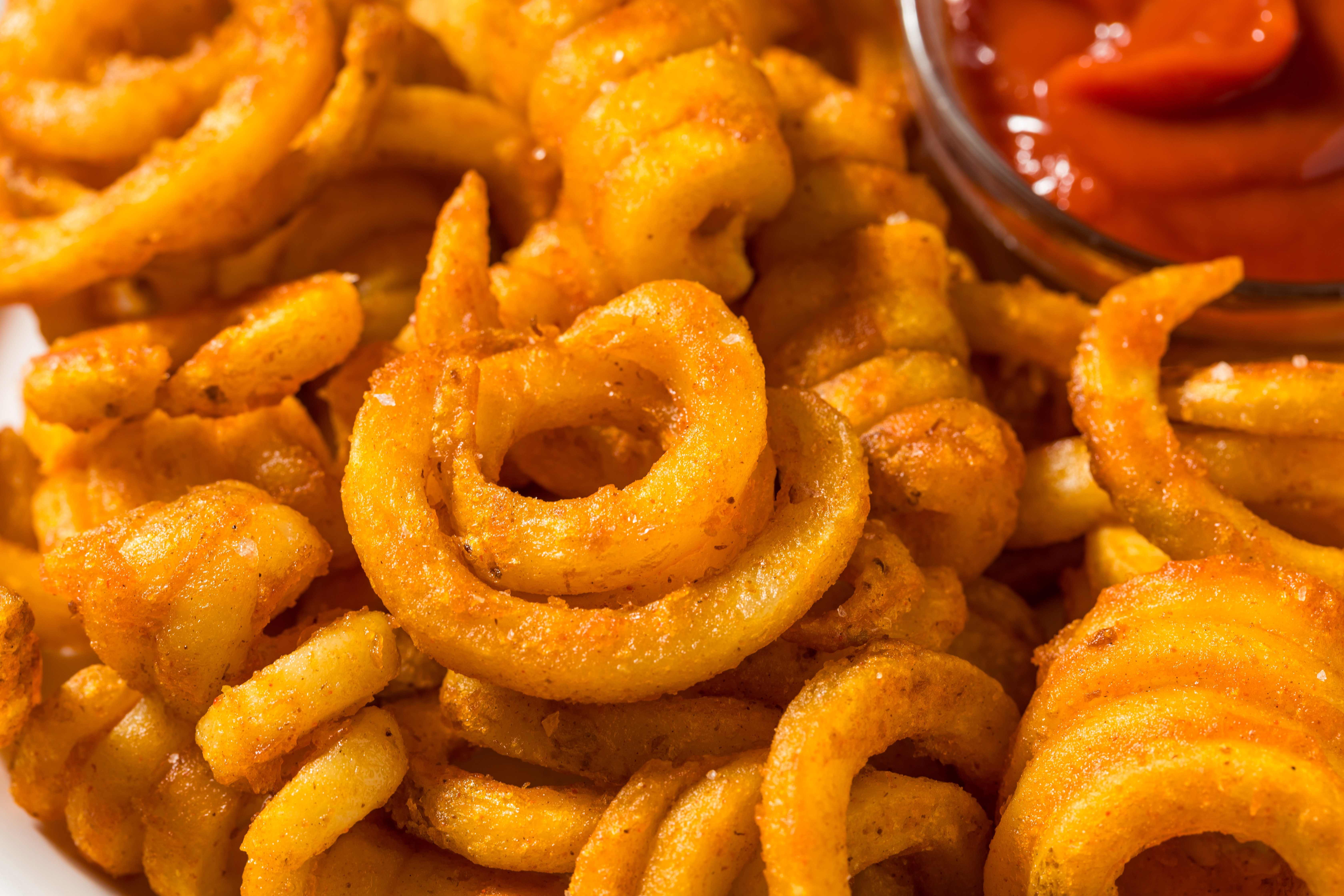 Close-up of crispy curly fries served with a side of ketchup