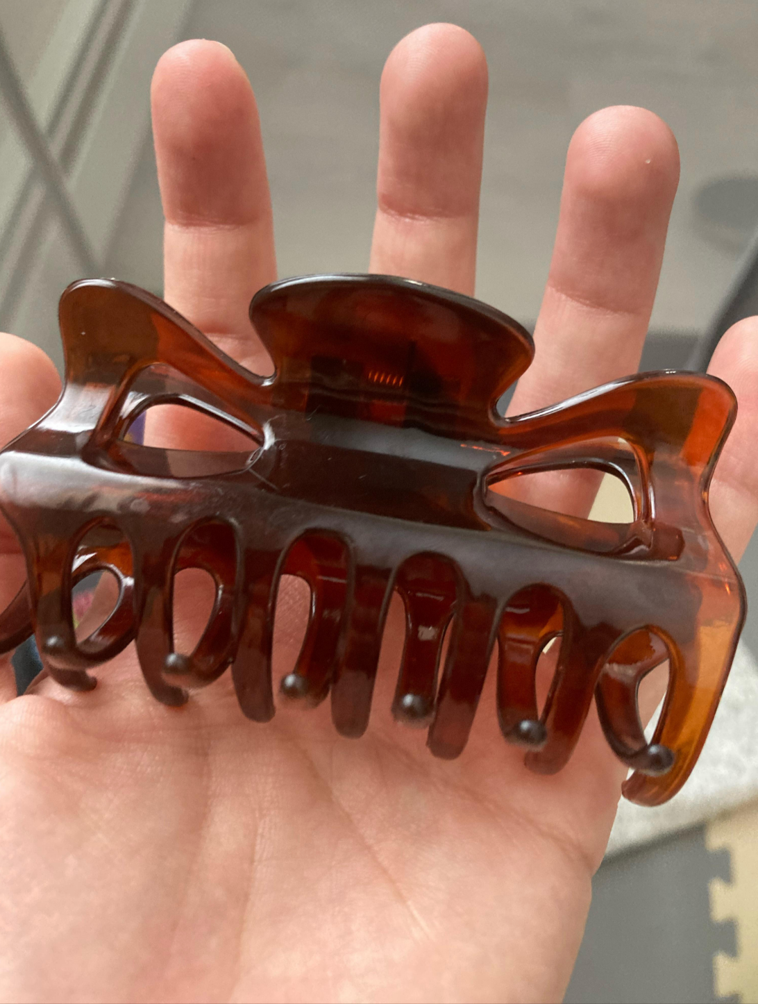 En hånd har et stort hårkloklipp med en elegant, gjennomskinnelig finish