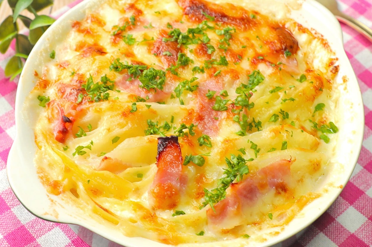 テーブルに置かれたグラタン。焼き目がついていて、パセリが散らされています。ピンクのチェックのクロスが敷かれています。