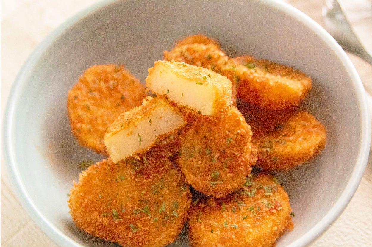 フライドポテトの一部はカットされており、上にハーブがトッピングされています。背景にソースの小皿が見えます。