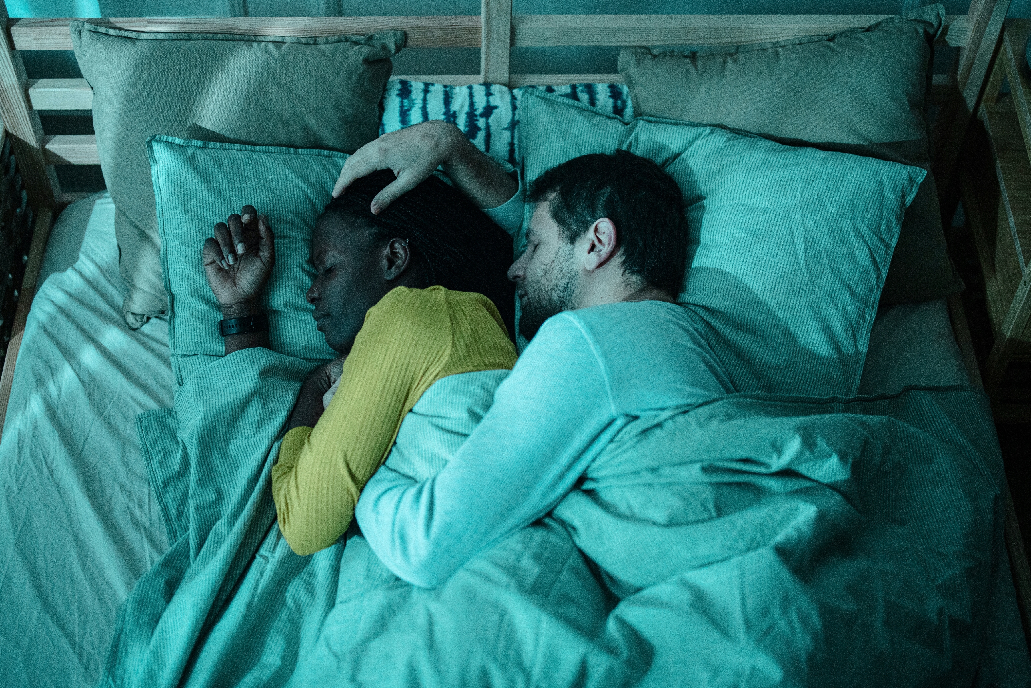 To personer sover fredelig i sengen, en iført et smartur. Den rolige innstillingen formidler avslapning og komfort