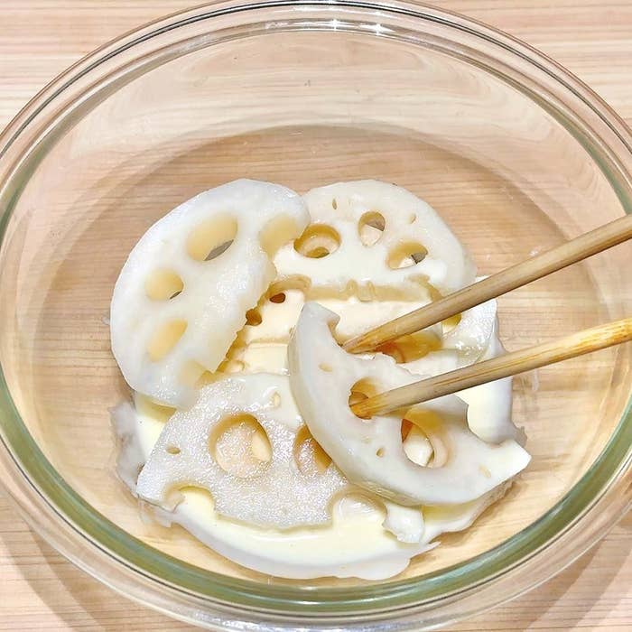 蓮根が透明なガラスのボウルに入れられており、箸で一切れが持ち上げられています。