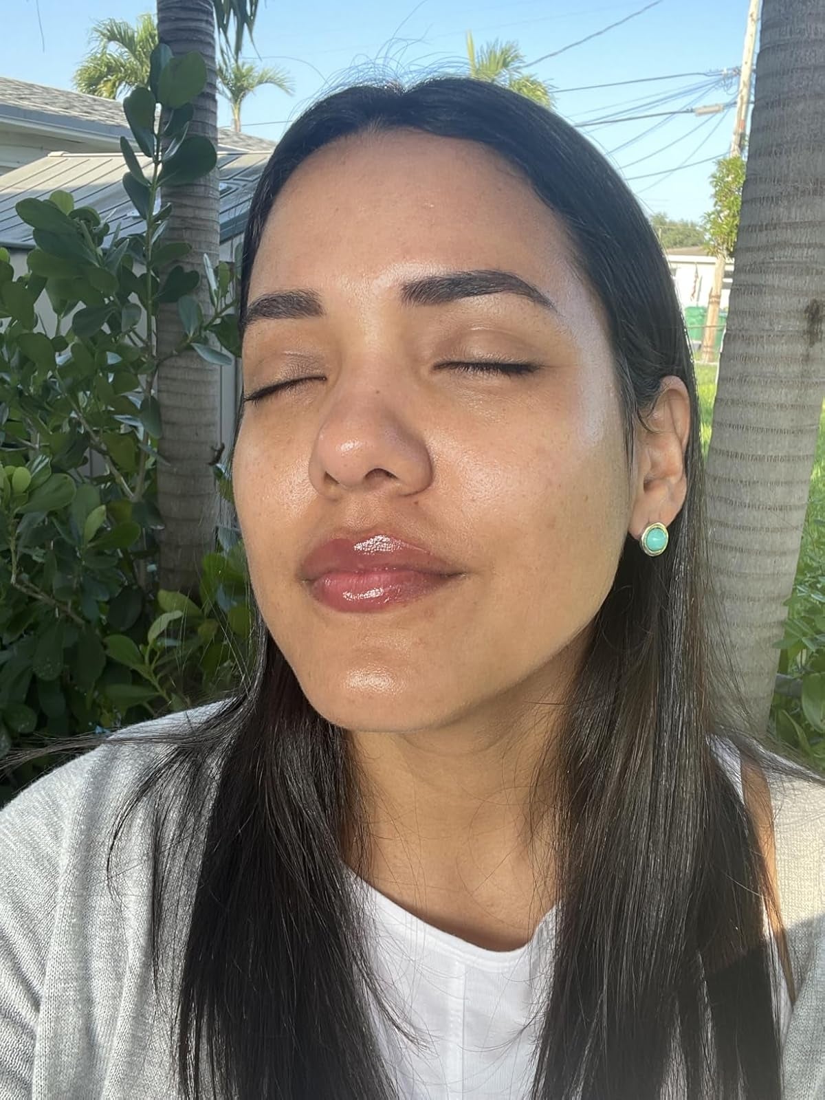 Person extracurricular  with eyes closed, wearing a achromatic  apical  and mint greenish  earrings, appearing relaxed successful  a sunny, earthy  setting