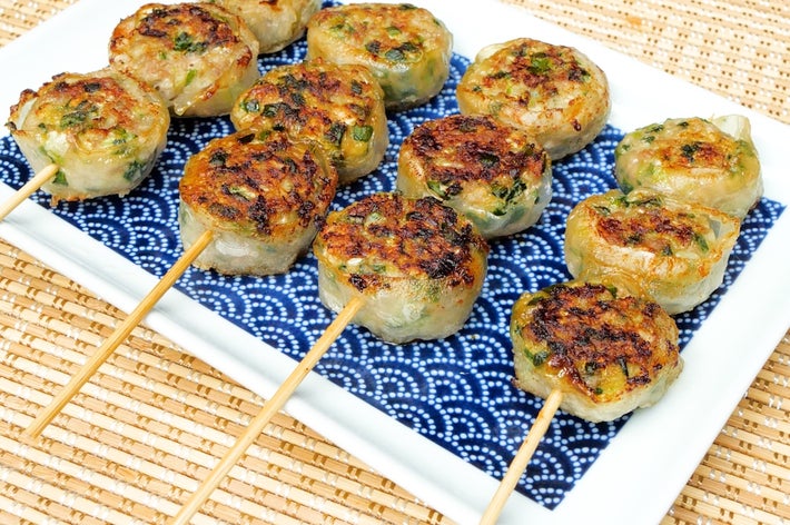 皿の上に串刺しの焼き餃子が並び、横に醤油の小皿が置かれている。