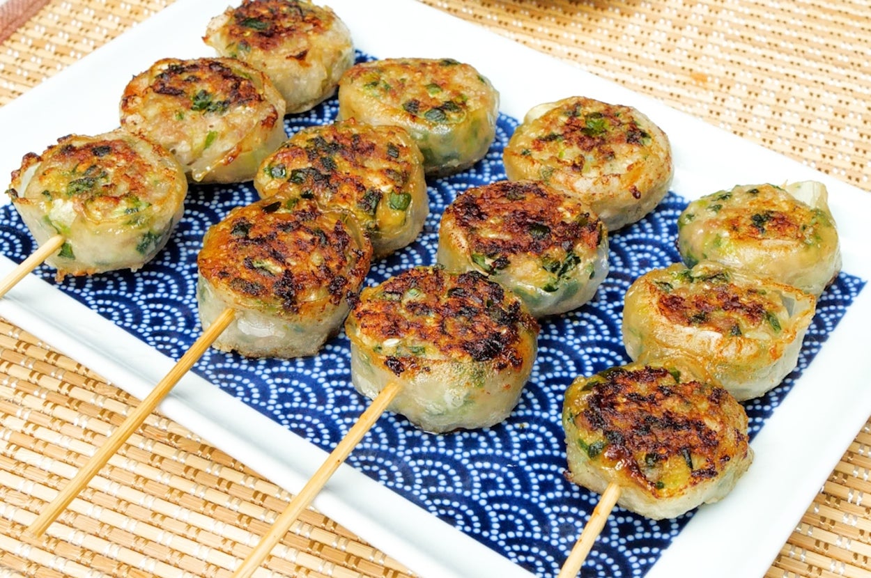 皿の上に串刺しの焼き餃子が並び、横に醤油の小皿が置かれている。