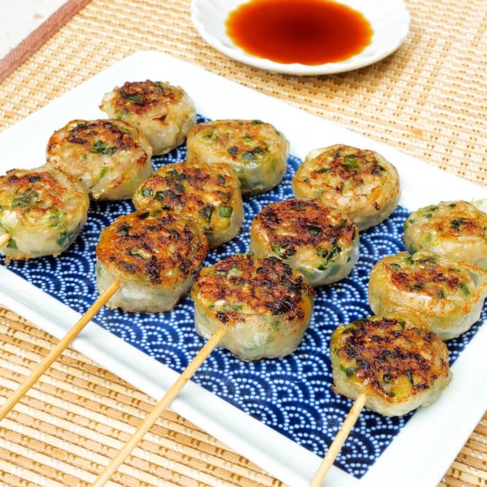 焼き鳥スタイルで串に刺さった餃子が、ソースと共に皿に載っている。