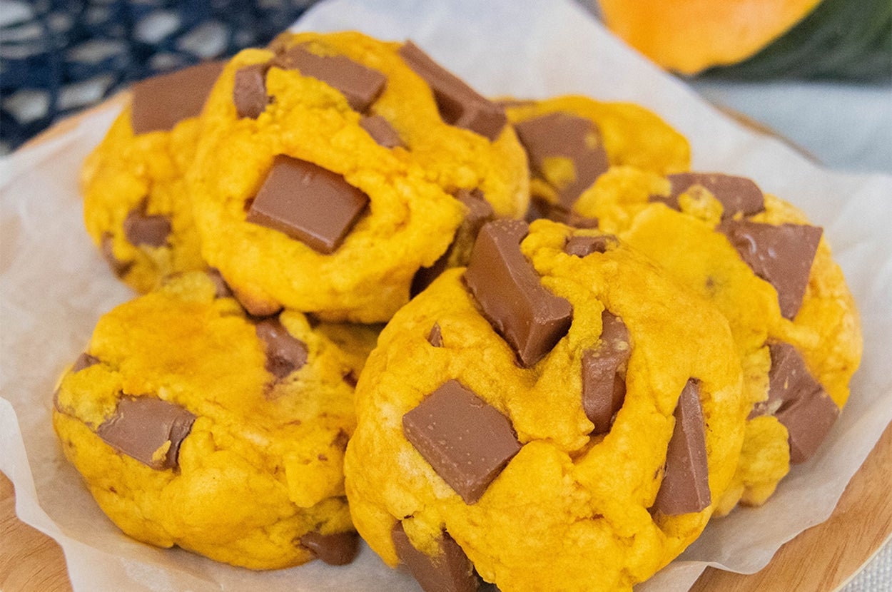 プレートに盛られたチョコレートチャンク入りのかぼちゃクッキー。背景にかぼちゃの一部が見える。