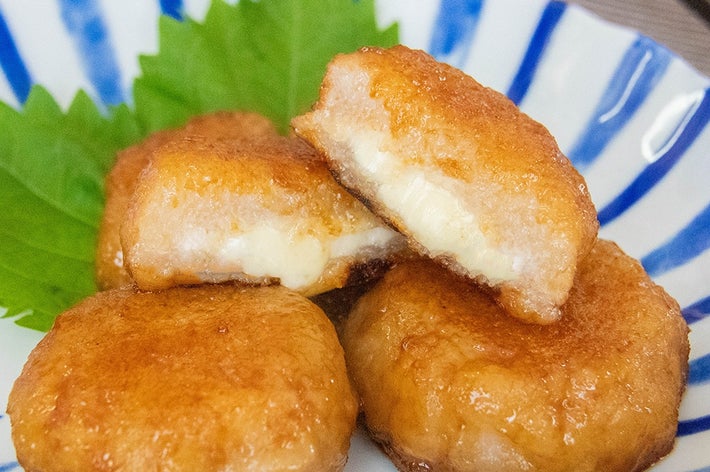 白い皿に盛られたチーズ入りれんこんもち。大葉が添えてある。