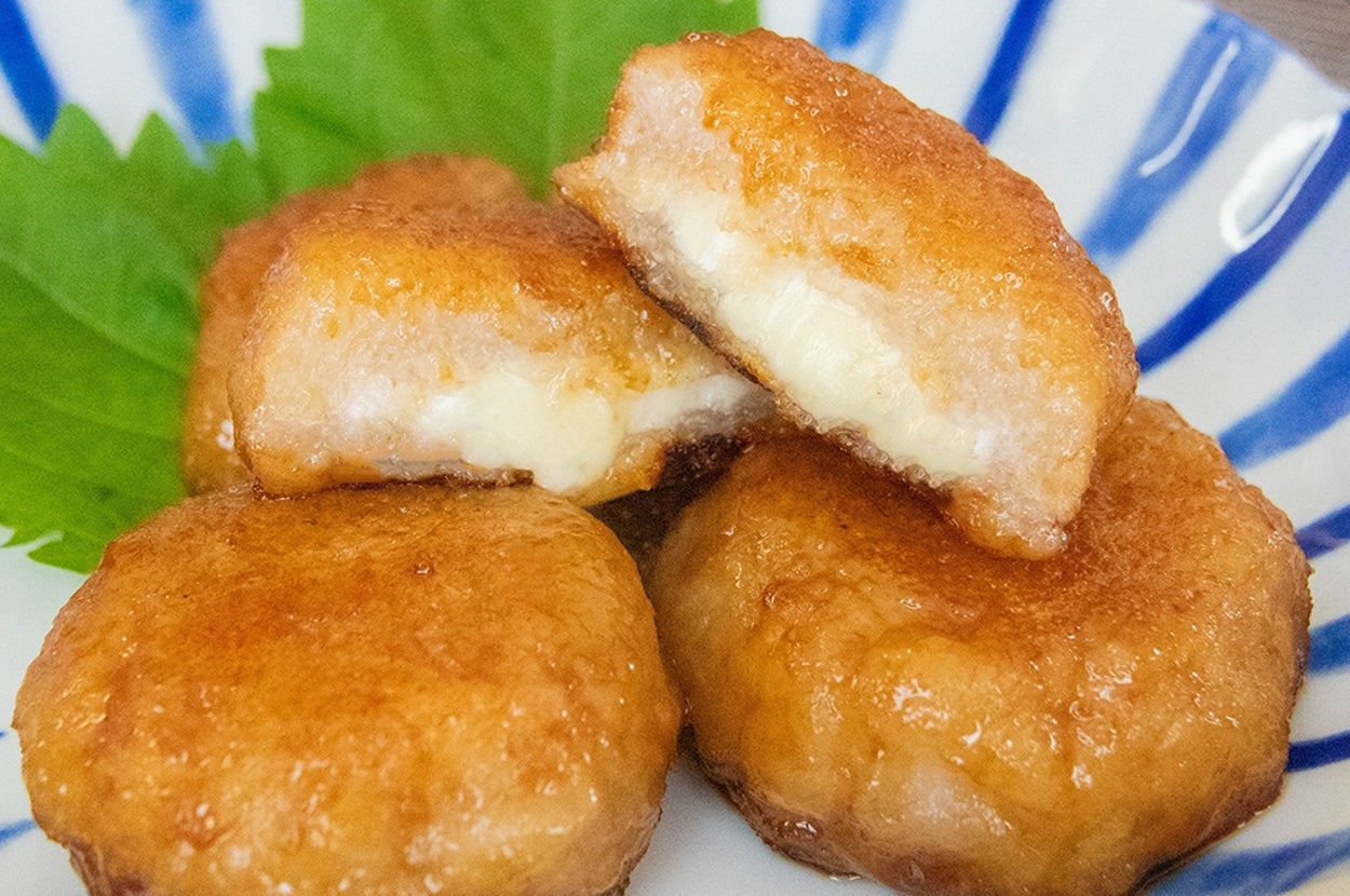 白い皿に盛られたチーズ入りれんこんもち。大葉が添えてある。