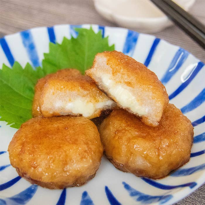 白い皿に盛られたチーズ入りれんこんもち。大葉が添えてある。
