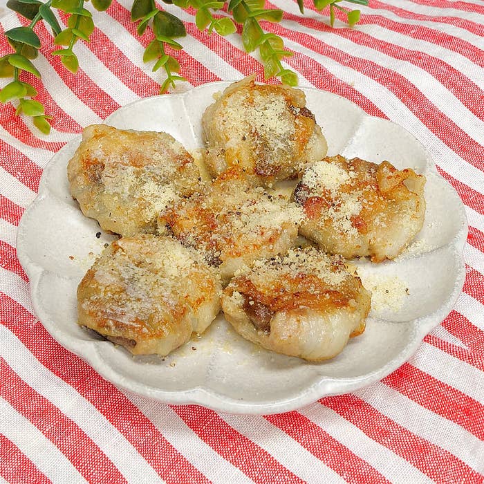 しいたけの肉巻き、上には粉チーズが振りかけられている。背景はストライプの布。