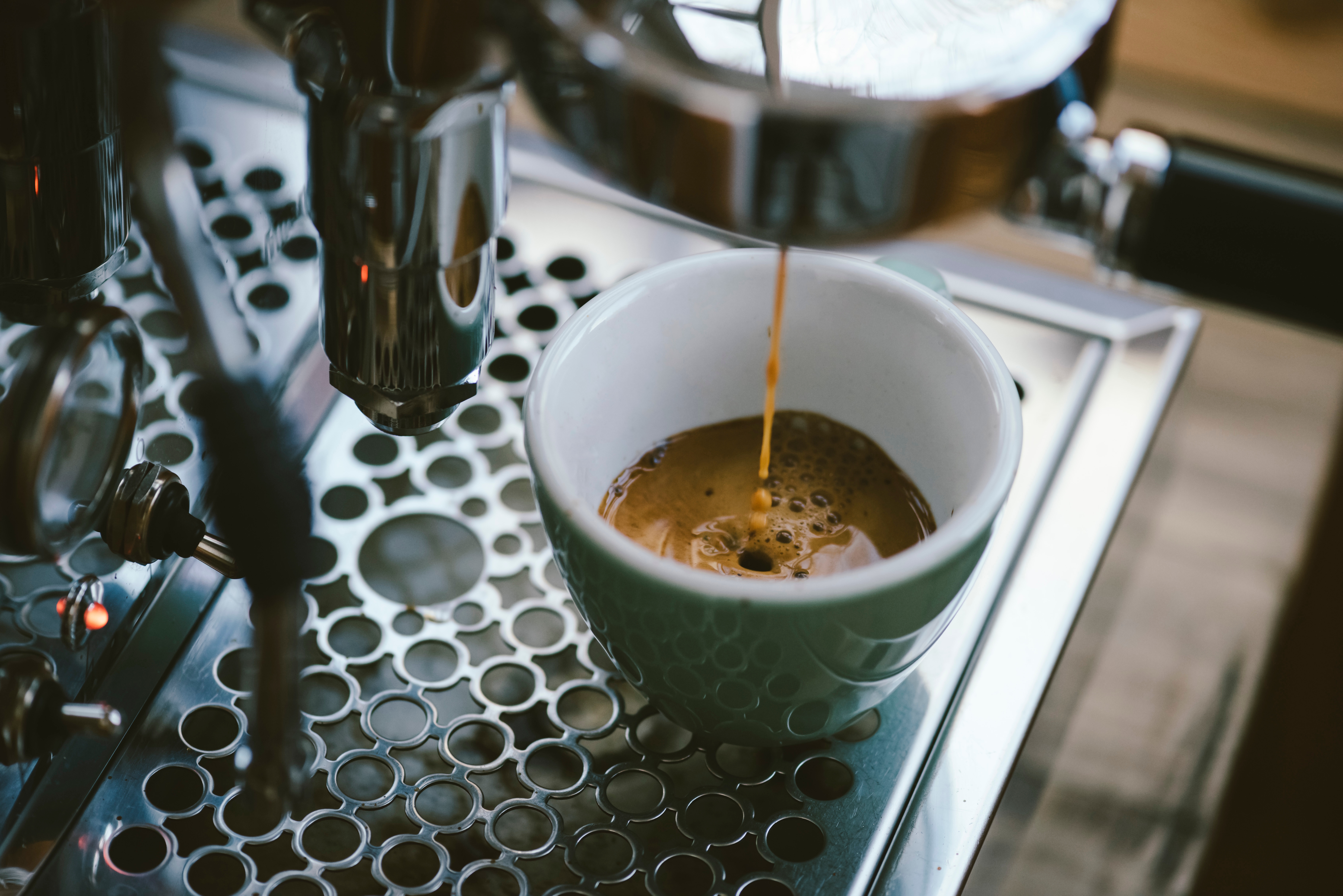 Espresso being freshly brewed into a white cup from a metallic espresso machine