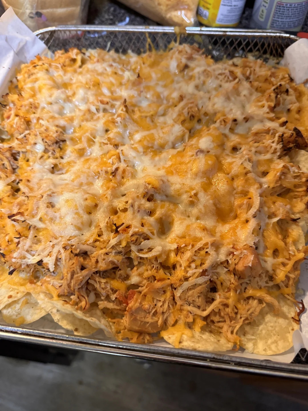 A tray of baked chicken nachos topped with melted cheese