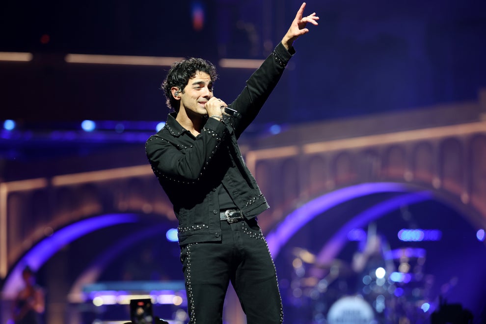 24 Bizarre Celeb Facts That Sound Fake, But Are 100% True 36 Singer on stage in embellished suit performing energetically with microphone, raising one hand while a band plays in the background