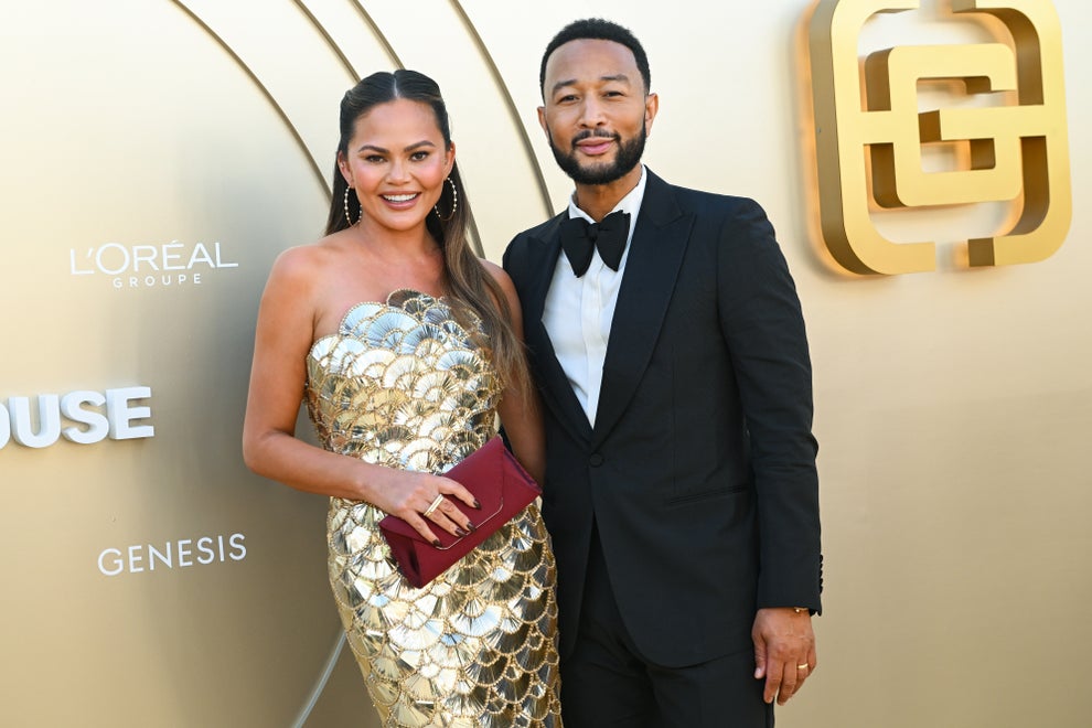 24 Bizarre Celeb Facts That Sound Fake, But Are 100% True 38 A woman in a strapless gold dress and a man in a black tuxedo pose together at an event with a logo backdrop