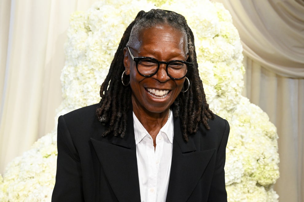24 Bizarre Celeb Facts That Sound Fake, But Are 100% True 34 Person smiling in formal attire with dreadlocks, wearing a blazer and shirt, against a floral backdrop at a celebrity event
