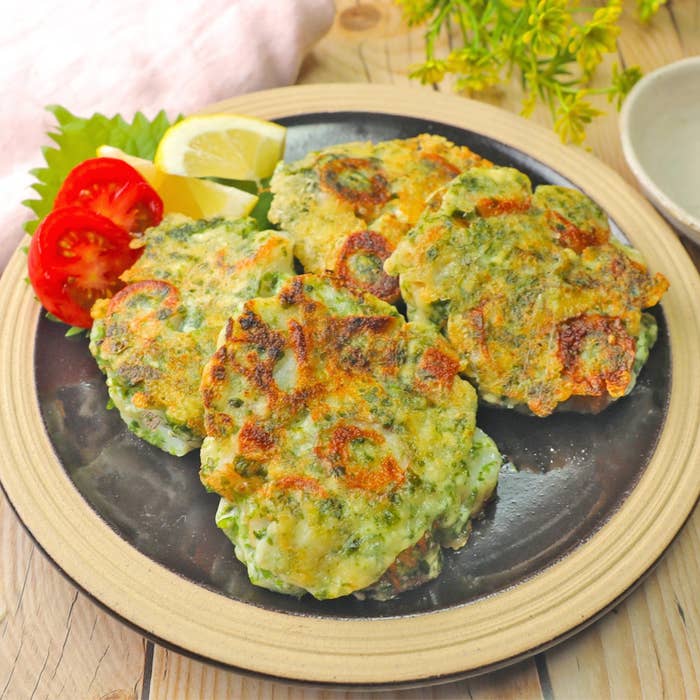 お皿に盛られた野菜と魚介のかき揚げ、トマトとレモンのスライスが添えられている。