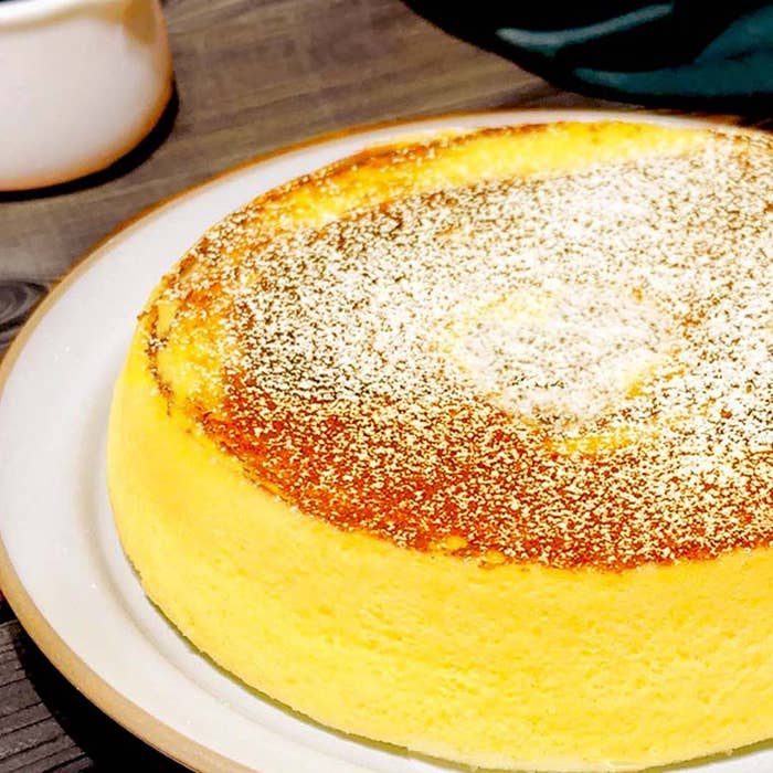 白いお皿にのったスフレタイプのチーズケーキ。表面には粉砂糖がかかっている。