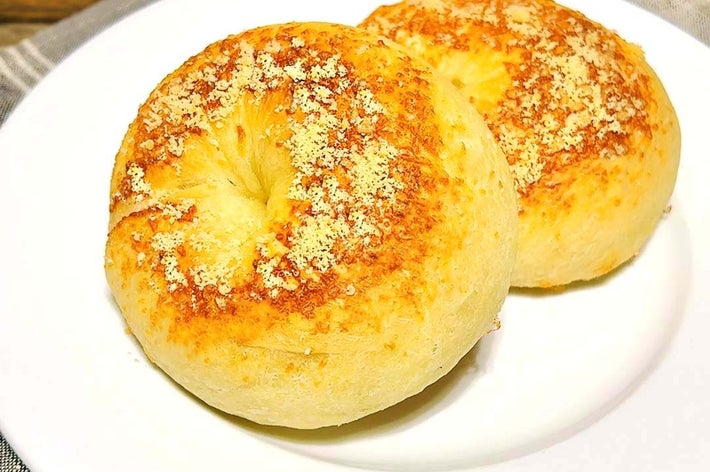 皿に乗った2つのチーズがトッピングされたベーグル。