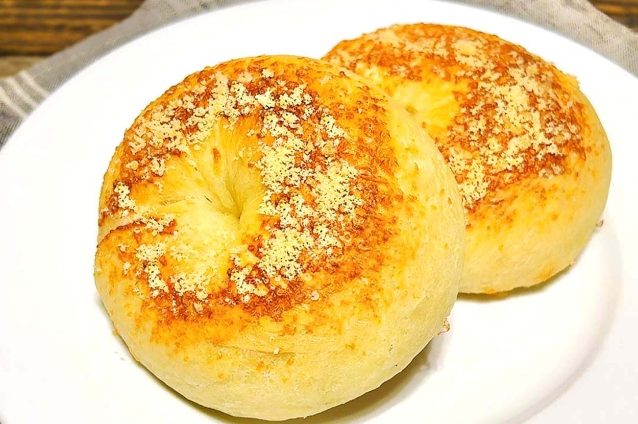 皿に乗った2つのチーズがトッピングされたベーグル。