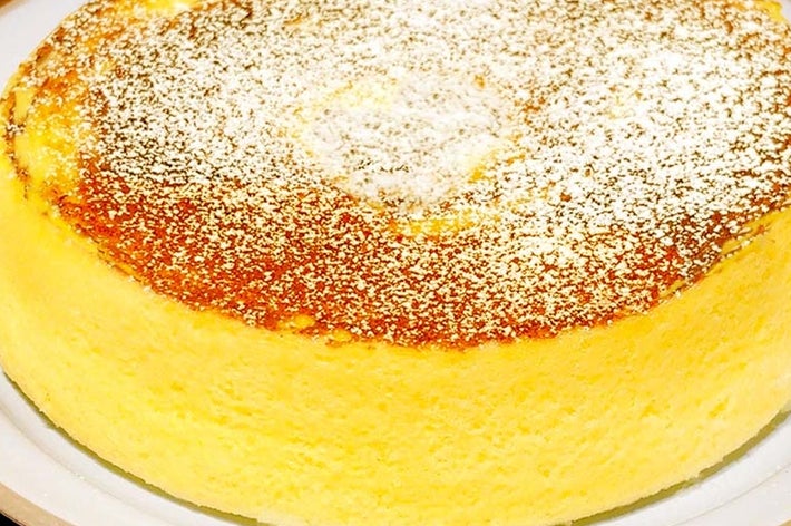 ふわふわのスフレチーズケーキが皿に盛られており、上には粉砂糖が軽く振りかけられている。