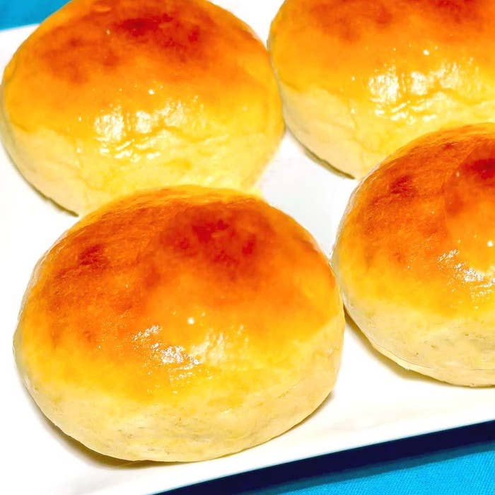 丸いパンが4つ、白い皿に並んでいます。表面はつややかで、焼きたてのように見えます。