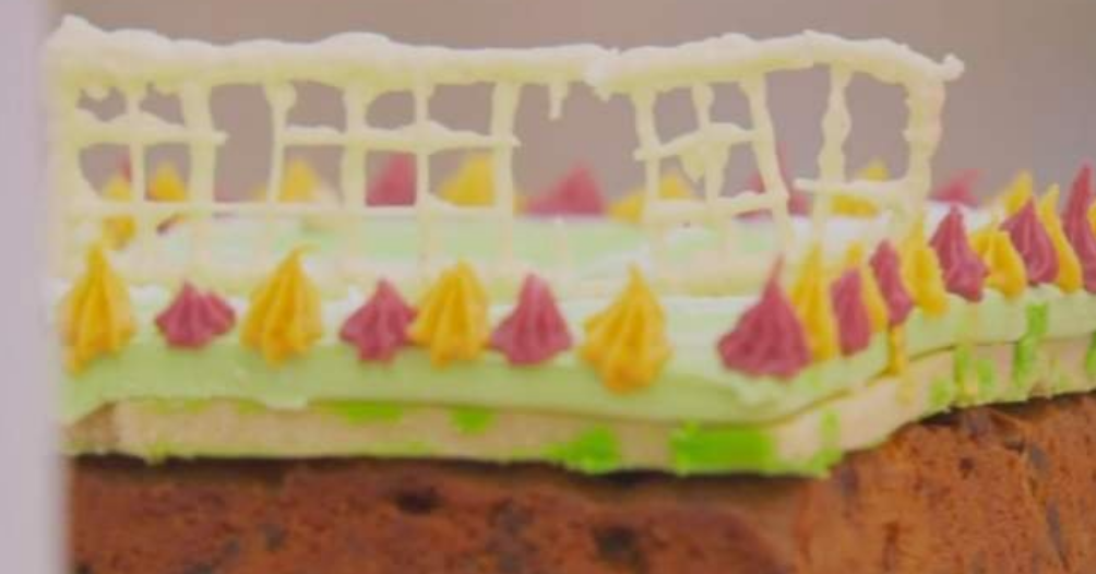 Cake decorated with white chocolate lattice and pointed dollops of frosting on top