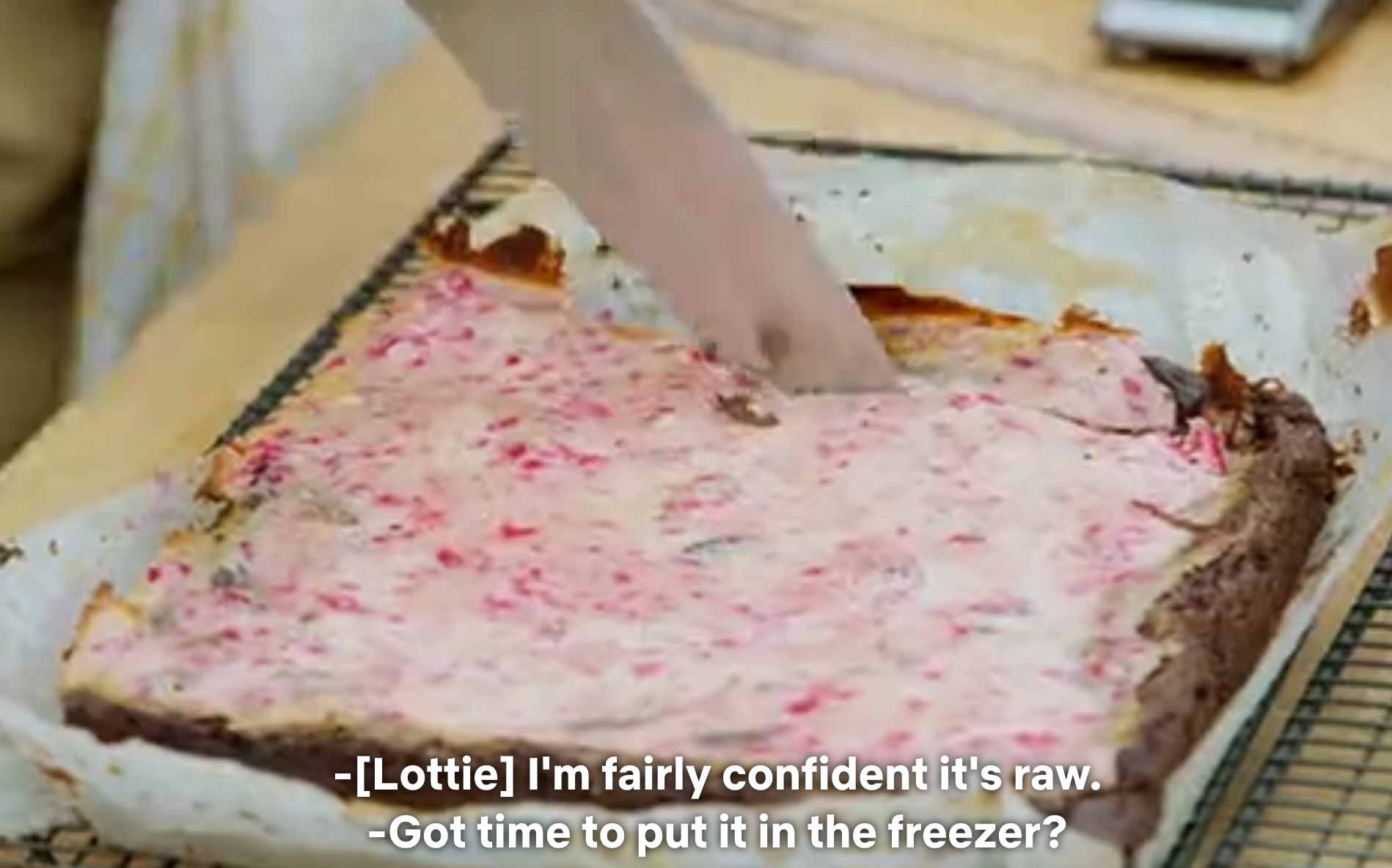 A person cuts a pink and brown dessert in a baking pan with captions discussing if it's raw and suggesting freezing it